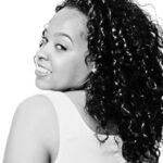 Black-and-white portrait of Lauren Lane looking over her shoulder, smiling softly.